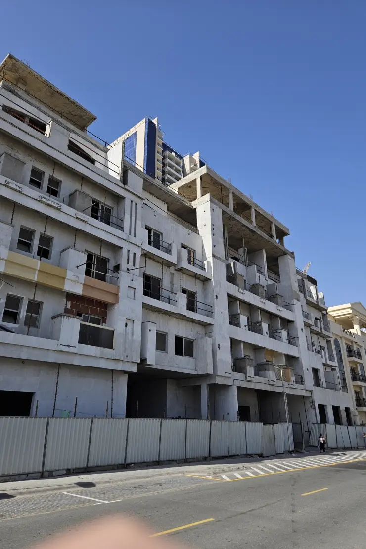 Paradise One construction progress photo (May 2026) — unfinished concrete shell on street frontage